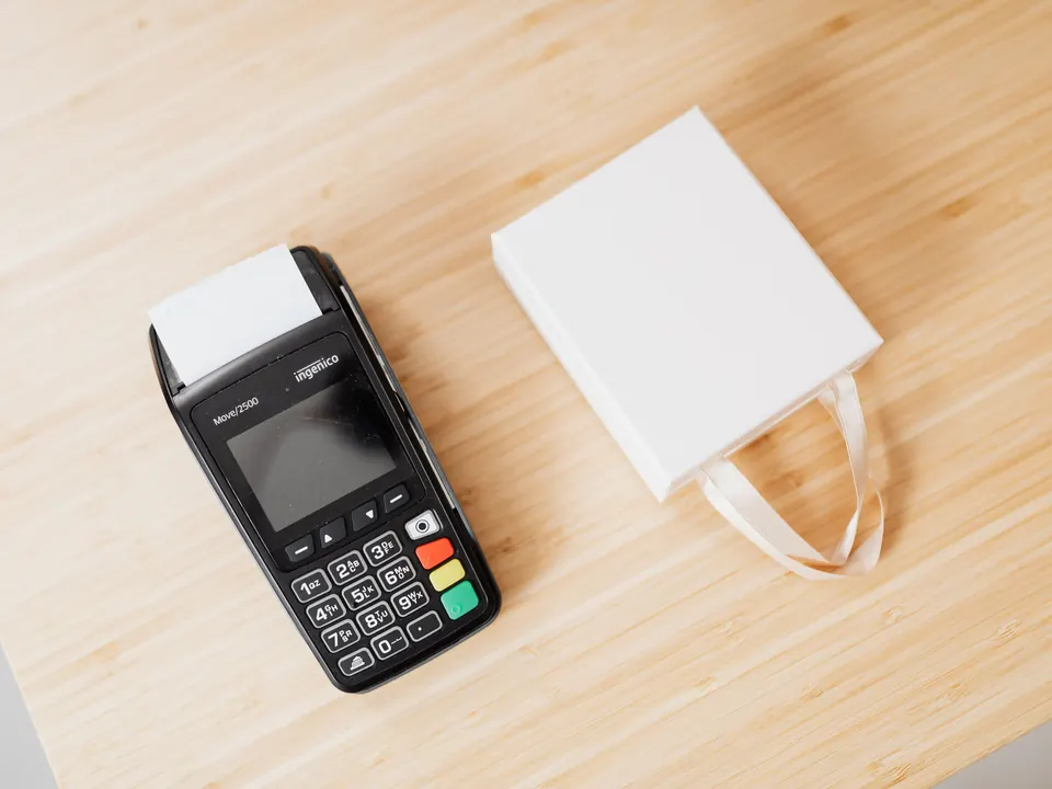 Kartenterminal und Geschenktüte auf einer hellen Holztheke